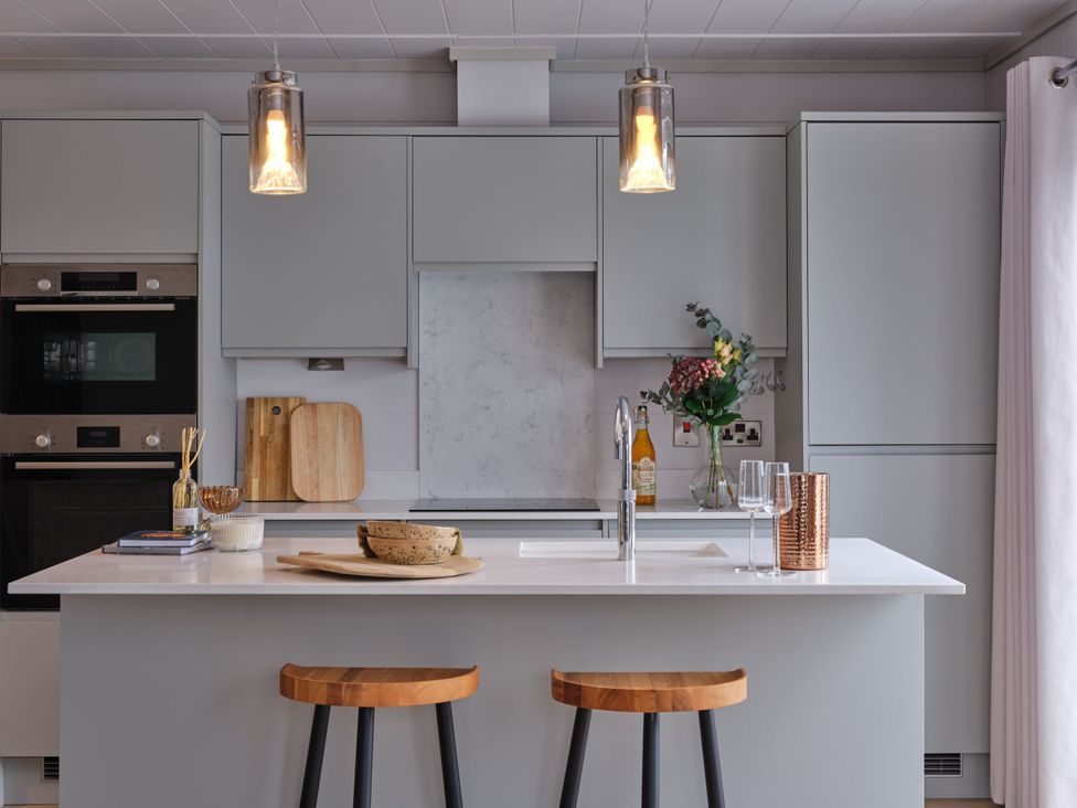 A kitchen with an island and bar stools at Epic Spa in Laugharne