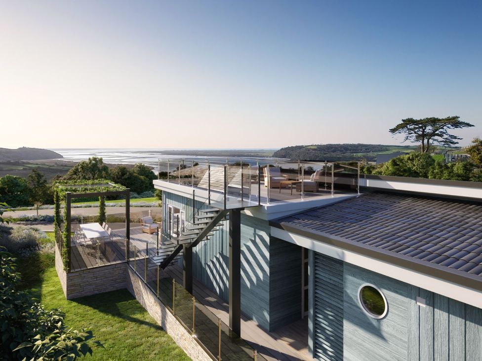 A house with a deck and stairs overlooking a landscape at Epic Spa in Laugharne