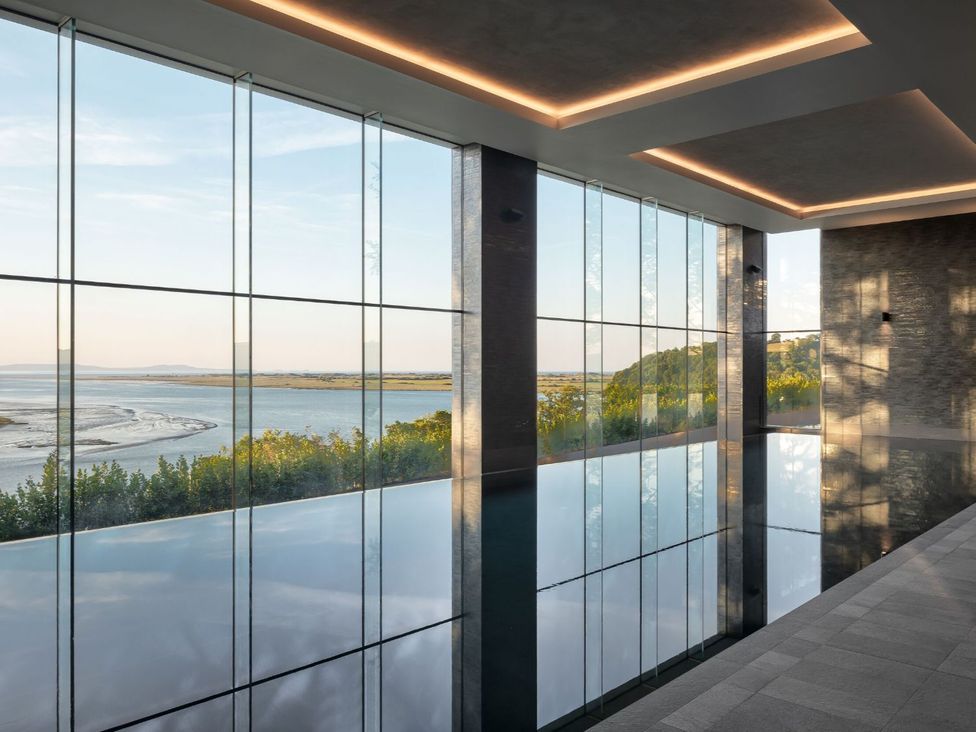 An indoor swimming area with large windows overlooking the landscape at Epic Spa (Pet) in Laugharne