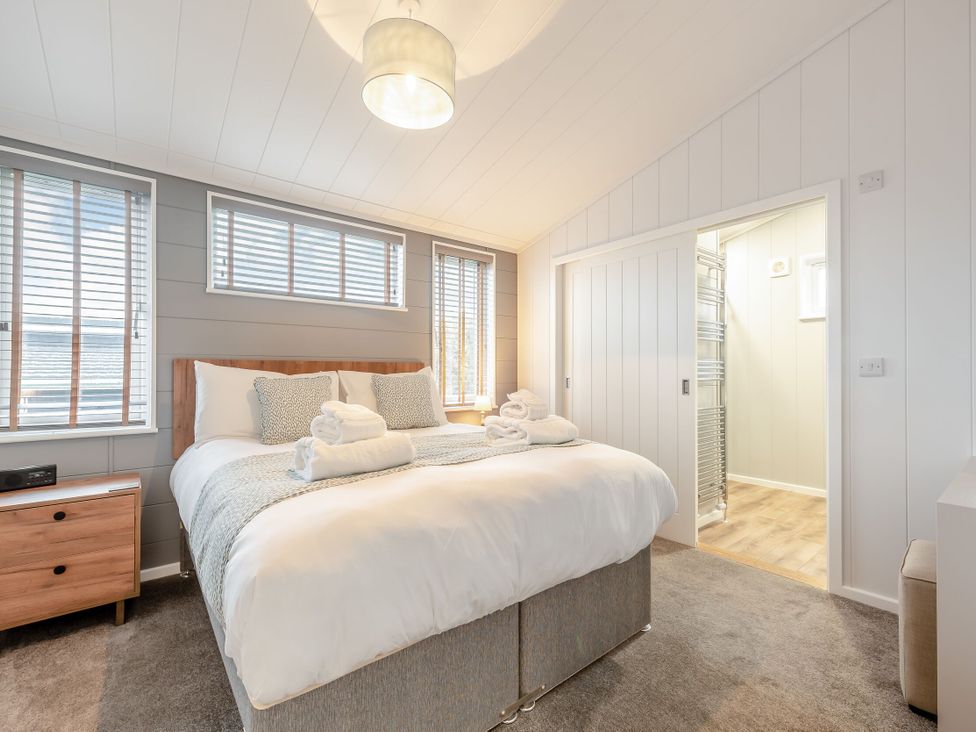 A bedroom with a bed and towels on it at Sonnet 3 Spa (Pet) in Laugharne