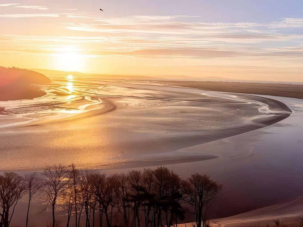 A river at sunset with trees along the bank at Sonnet 3 Roof Terrace Spa, Laugharne