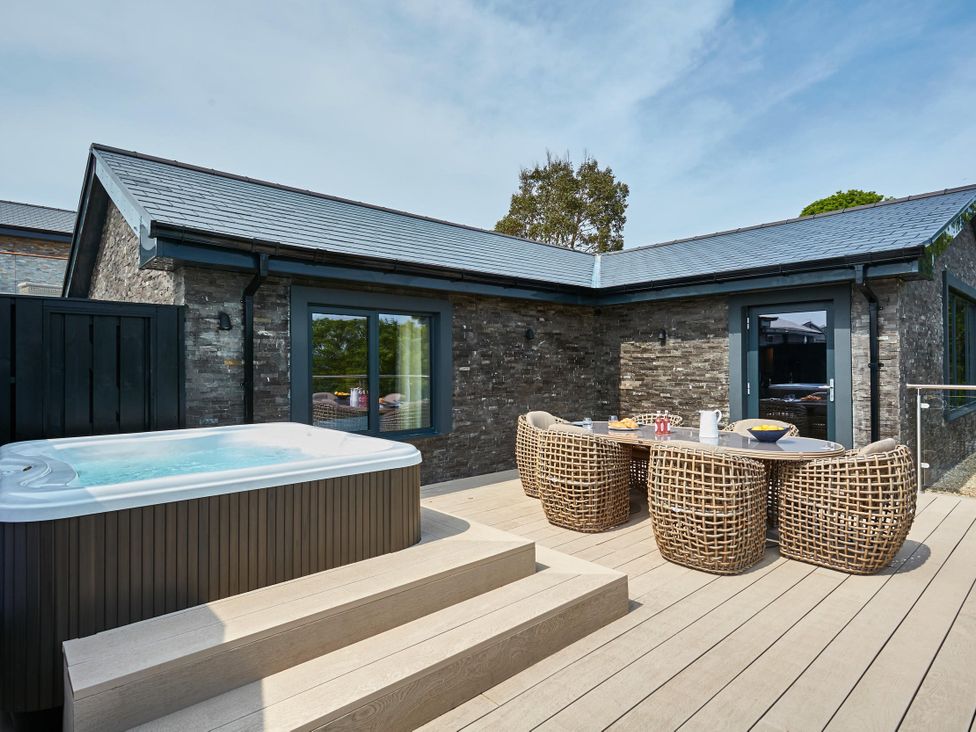 An outdoor area with a jacuzzi and seating furniture at Glan Y Mor in Laugharne