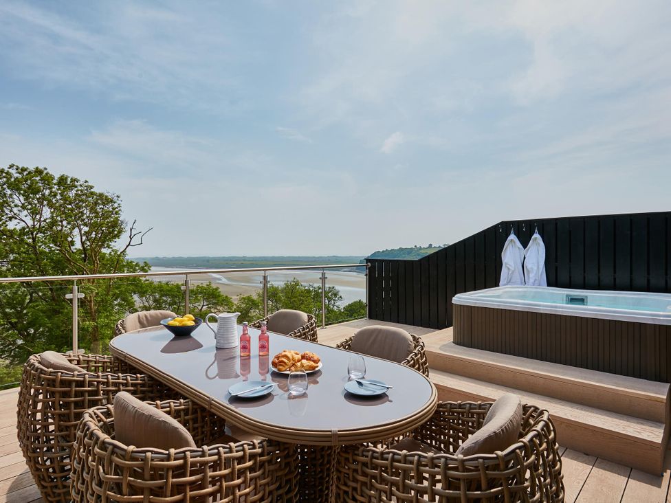 An outdoor dining area with a table and chairs overlooking a view at Glan Y Mor in Laugharne