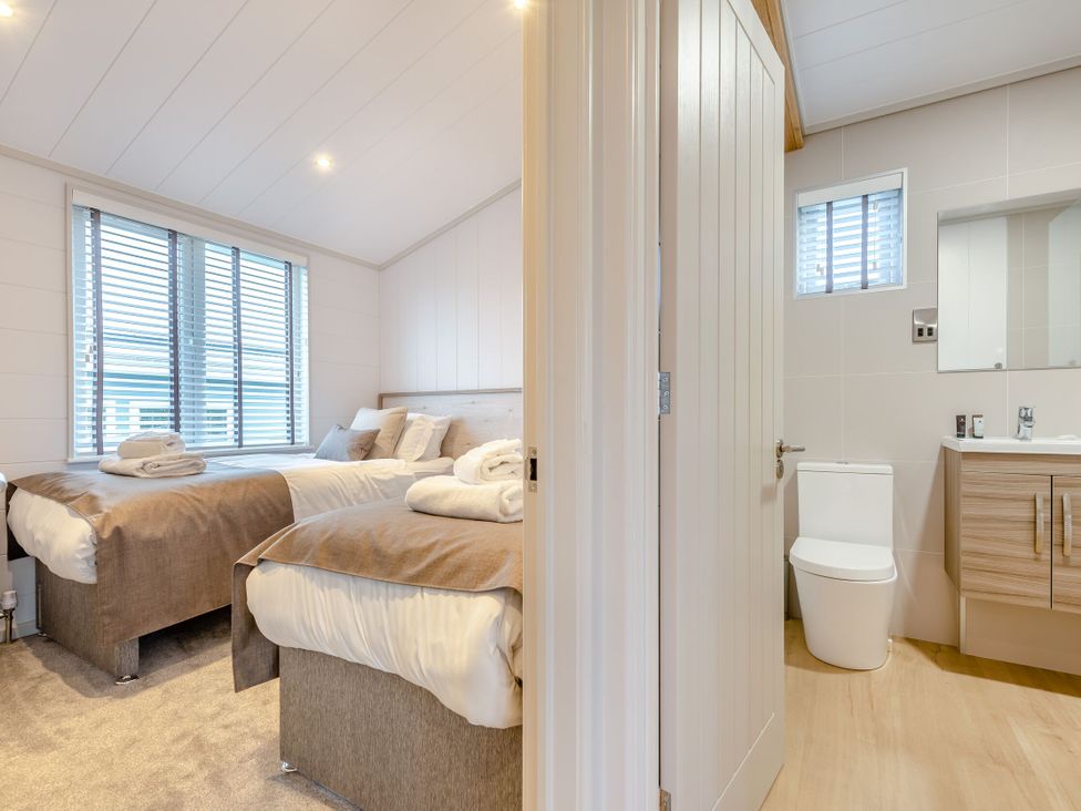 A bedroom with beds and an attached bathroom at Epic Spa (Roof Terrace) (Pet) in Laugharne