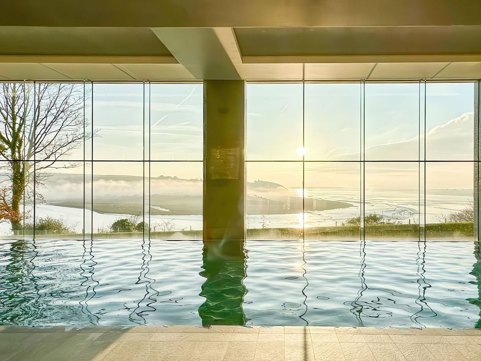 A spa area with a swimming pool and large windows overlooking a landscape at Epic Spa (Roof Terrace) (Pet) in Laugharne