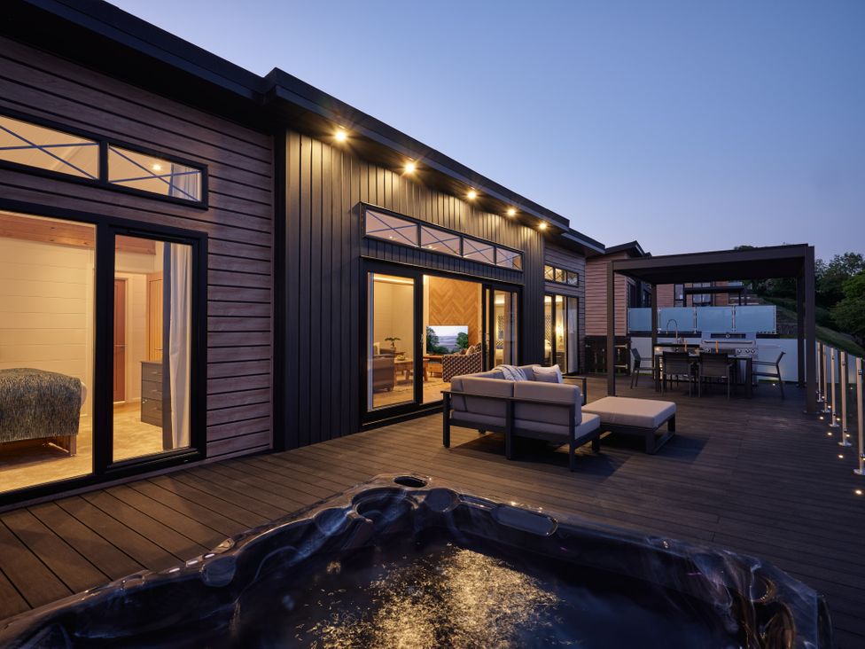 A deck with a hot tub and outdoor seating at Canto Spa in Laugharne