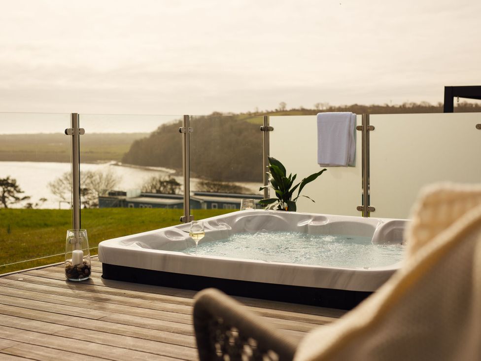 A hot tub with a glass and towel at Apex Spa (Pet) in Laugharne