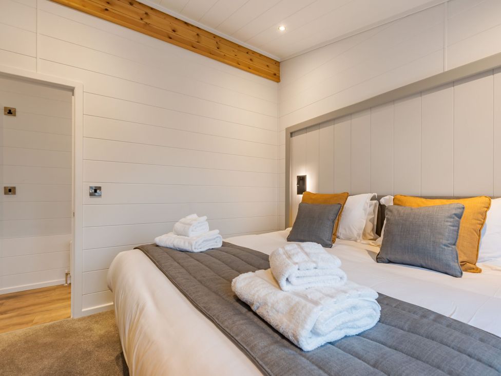 A bedroom with a bed and towels at Apex Spa (Pet) Laugharne