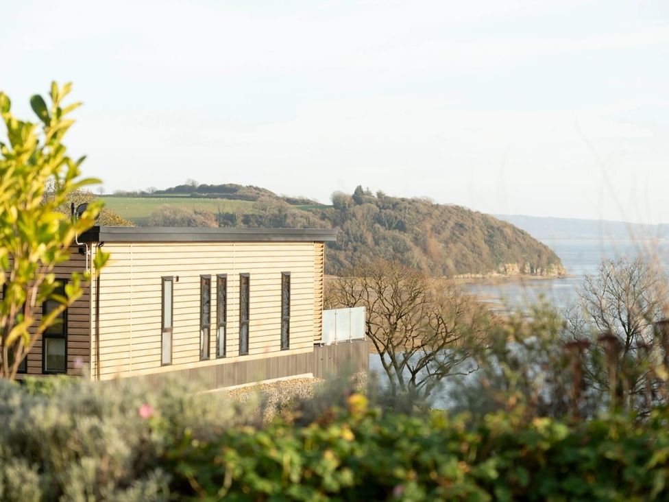 A building with a glass railing overlooking trees and hills at Solace in Laugharne
