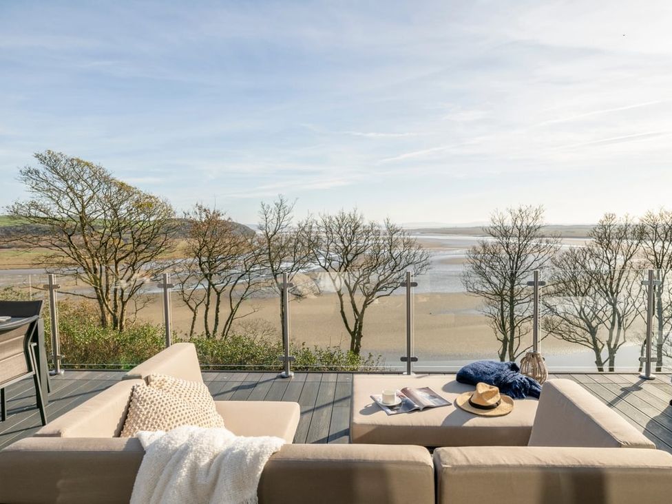 An outdoor seating area with a couch and coffee table overlooking the water at Solace in Laugharne