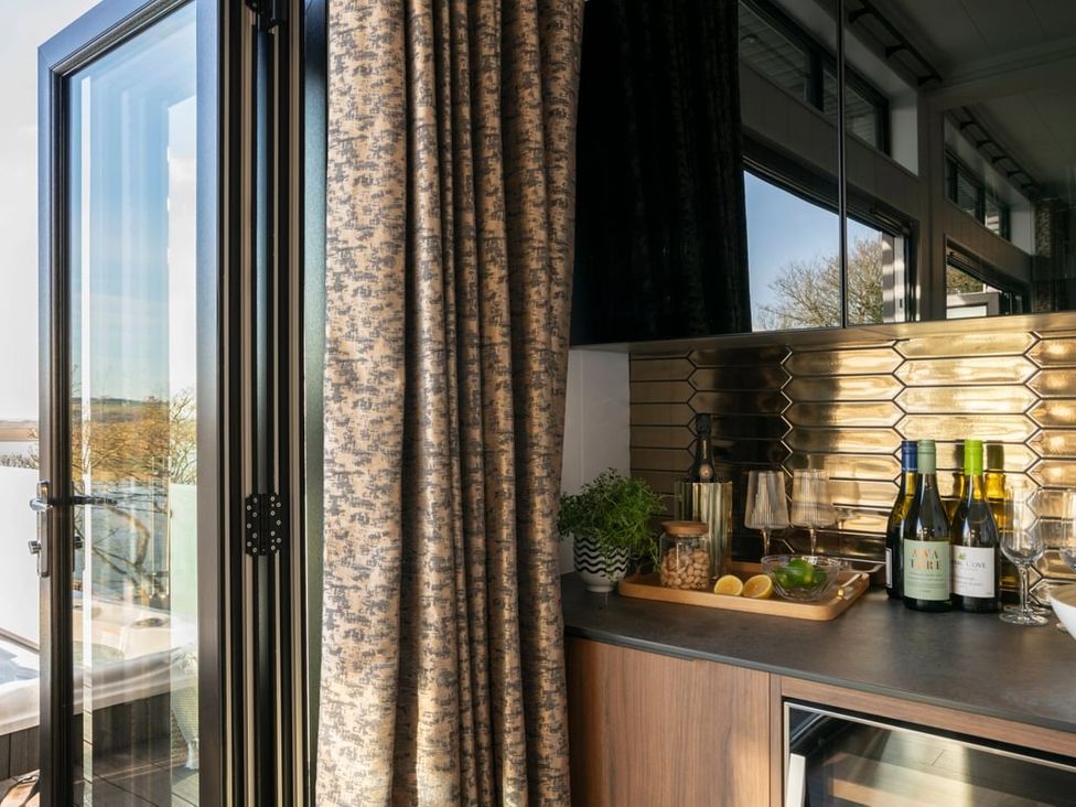 A kitchen area with window, bottles, glasses, and a cocktail shaker at Solace in Laugharne