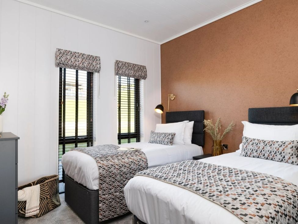 A bedroom with two beds and a flower vase at Solace in Laugharne