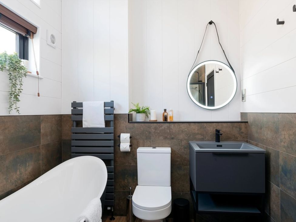 A bathroom with a bathtub, toilet, and sink at Solace in Laugharne