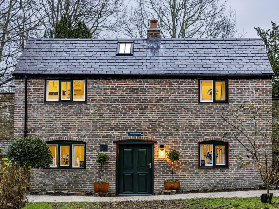 A brick house with a green front door and multiple windows at The Gardeners Cottage in Lytham St. Annes