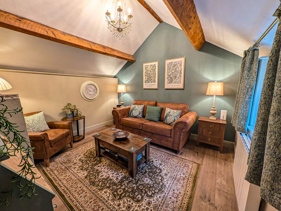 A living room with a sofa, armchair, and coffee table at The Gardeners Cottage in Lytham St. Annes