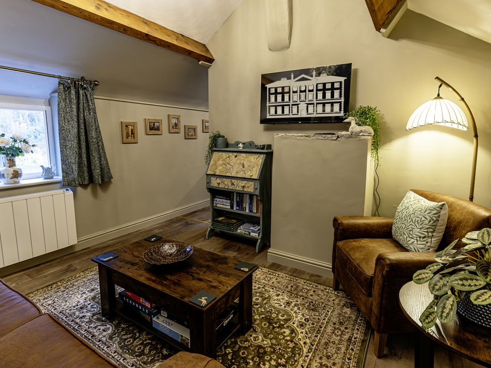 A living room with a window, coffee table, and seating area at The Gardeners Cottage in Lytham St. Annes