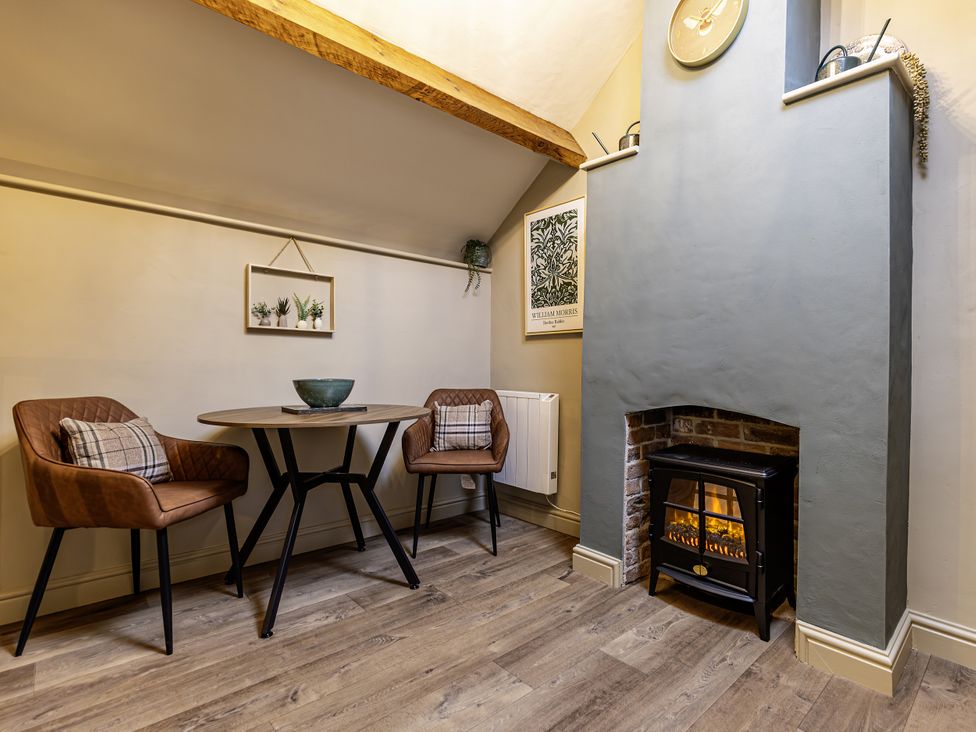 A snug with a table and chairs and a fireplace at The Gardeners Cottage in Lytham St. Annes