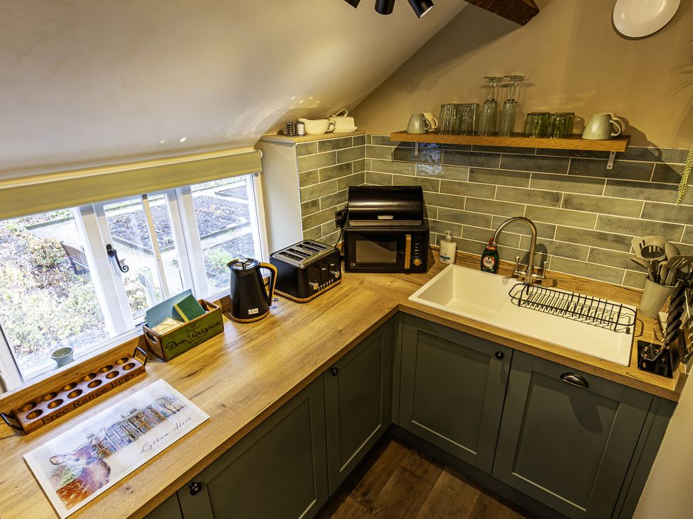 A kitchen with a sink and countertop appliances at The Gardeners Cottage in Lytham St. Annes