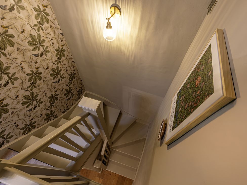 A staircase with a light fixture and framed picture at The Gardeners Cottage in Lytham St. Annes