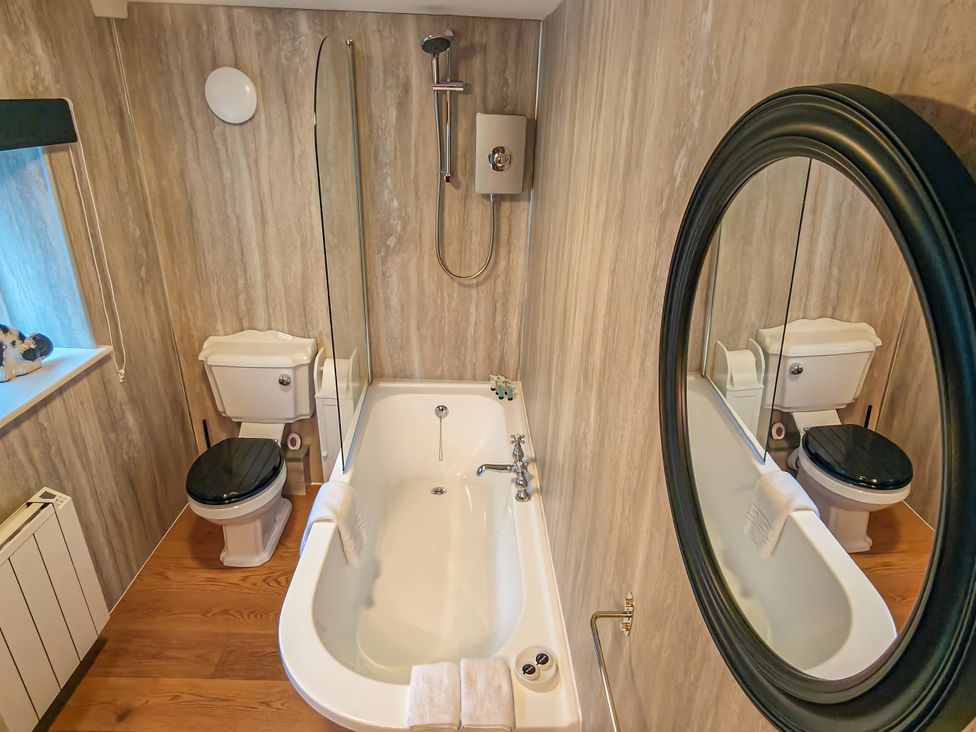 A bathroom with a bathtub and toilet at The Gardeners Cottage in Lytham St. Annes