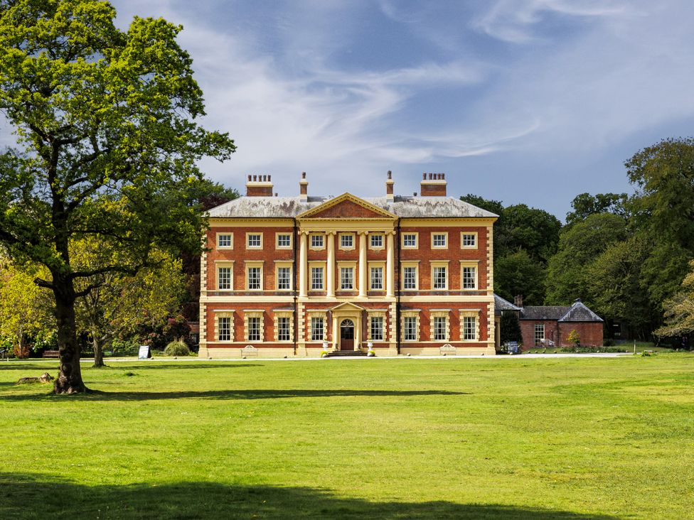 A large building surrounded by grass and trees at The Gardeners Cottage at Lytham Hall Lytham St. Annes