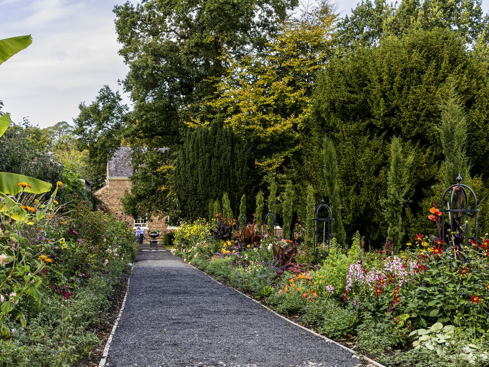 A garden with a pathway bordered by flower beds at The Gardeners Cottage at Lytham Hall, Lytham St. Annes