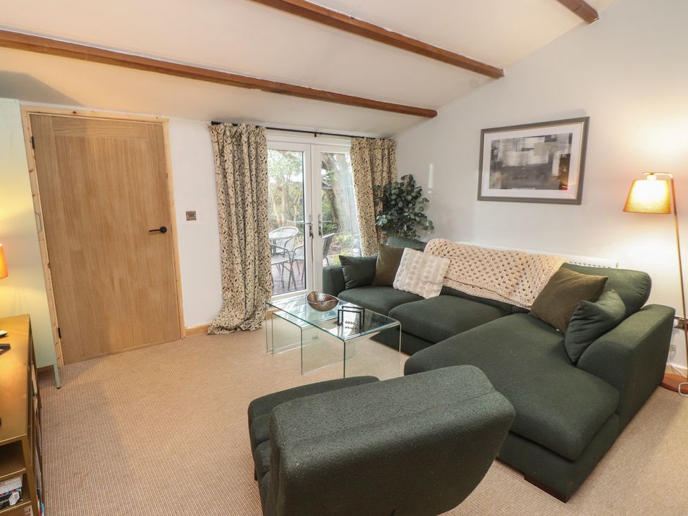 A living room with a green couch and glass coffee table at 20 Chatham Log Cabins Caernarfon