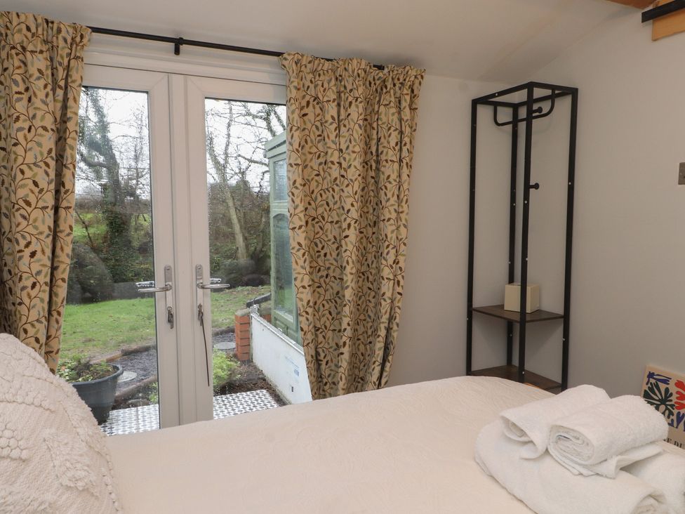 A bedroom with double doors leading to an outdoor area at 20 Chatham Log Cabins in Caernarfon