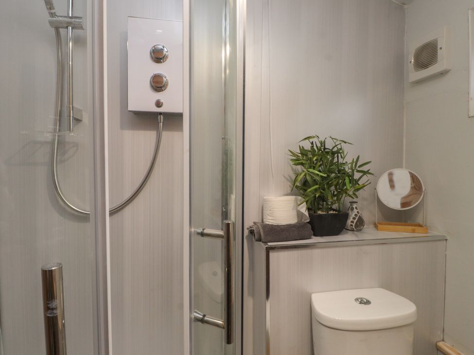 A bathroom with a shower and toilet at 20 Chatham Log Cabins Caernarfon
