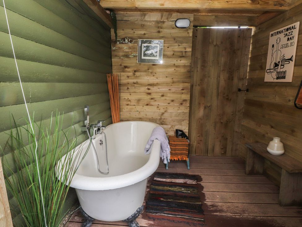 A bathroom with a bathtub and wooden walls at 20 Chatham Log Cabins Caernarfon