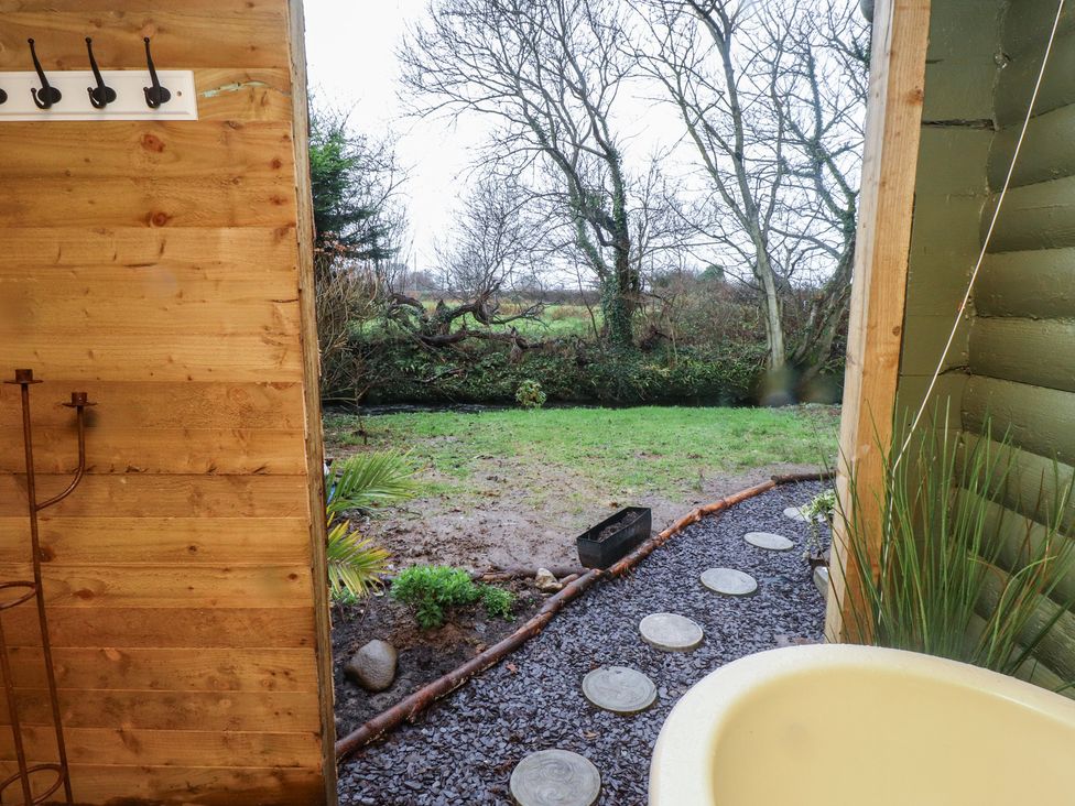 An outdoor area with a tub and a garden view at 20 Chatham Log Cabins in Caernarfon