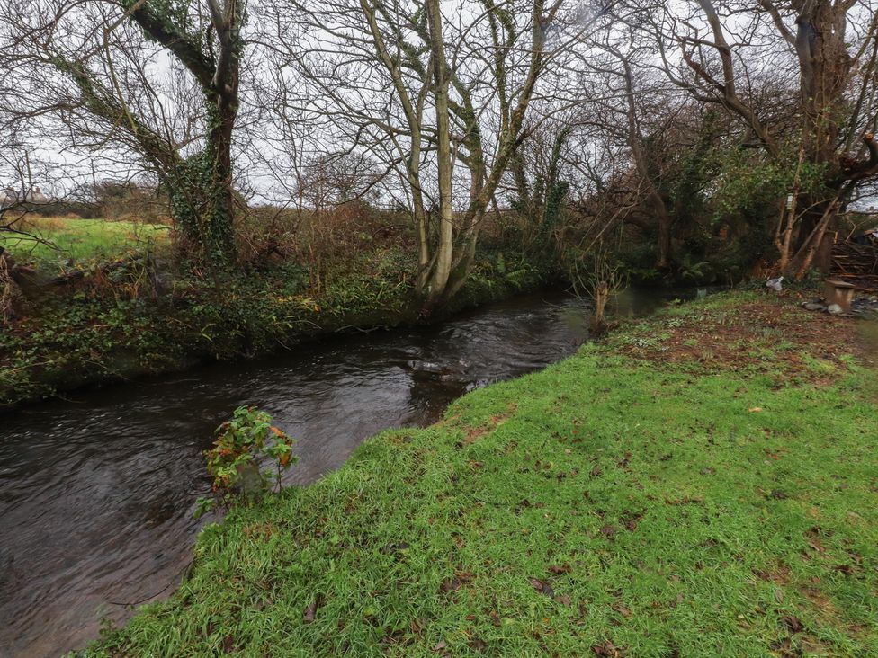 A stream surrounded by grass and trees at 20 Chatham Log Cabins Caernarfon