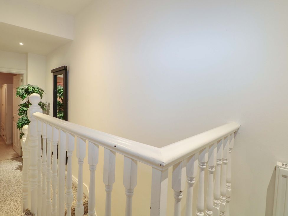 A hallway with a staircase and a mirror at 213 Gordon Avenue in Camberley