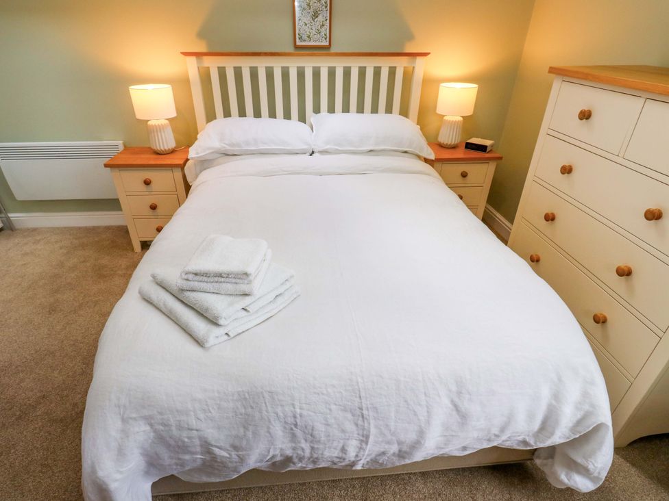 A bedroom with a bed, lamps, towels, and a dresser at Chapel House Annex, Scholes