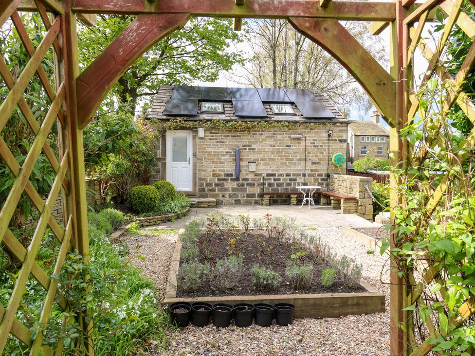 A garden with a stone building and flower bed at Chapel House Annex Scholes