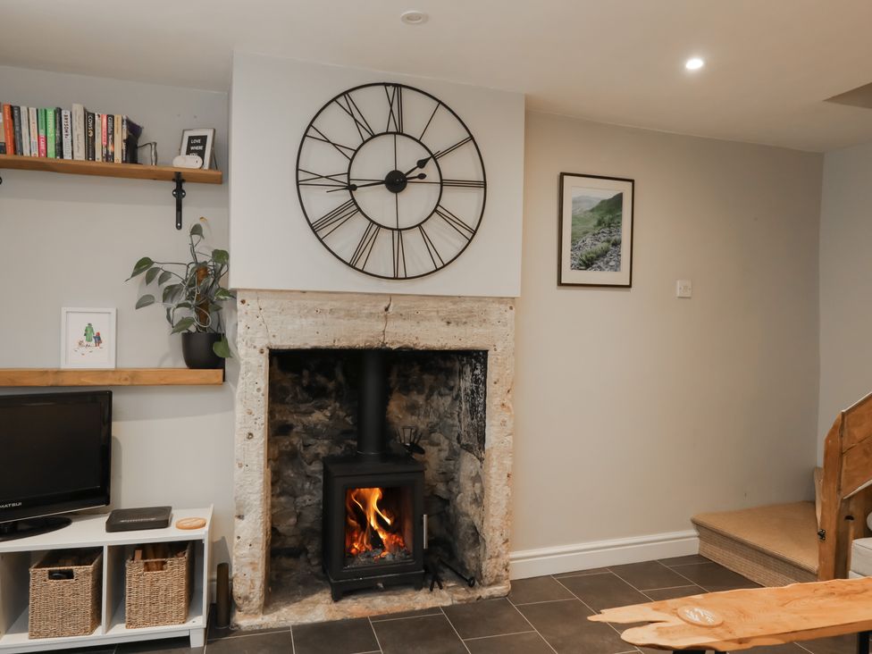 A living room with a wood burner and books on a shelf at Lavender Cottage in Bradford-on-Avon