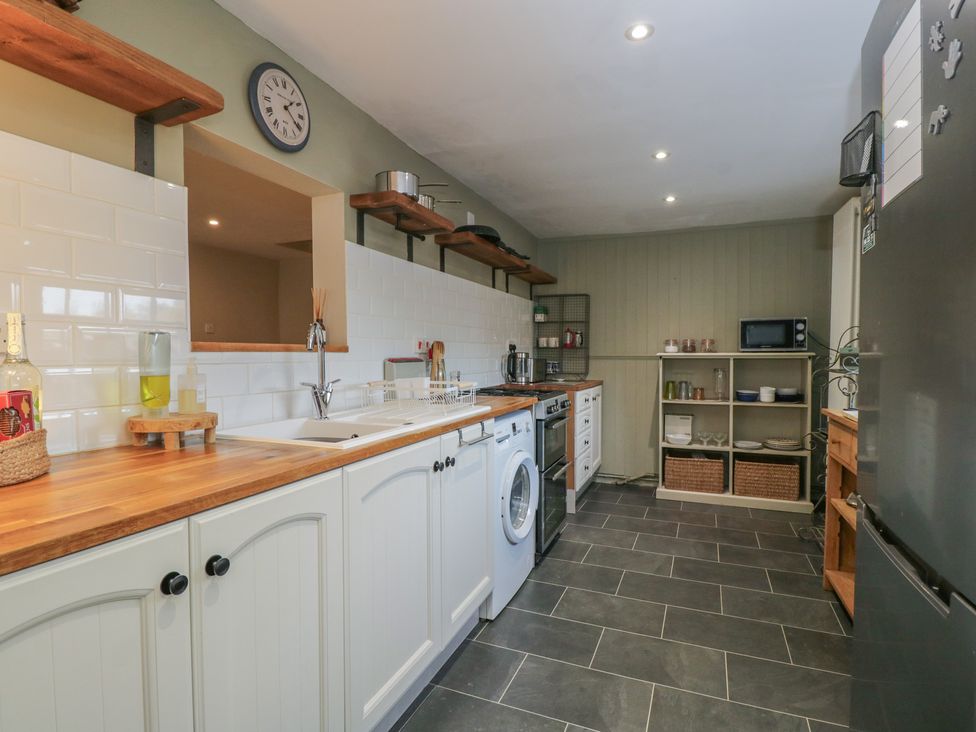 A kitchen with appliances and shelves at Lavender Cottage in Bradford-on-Avon
