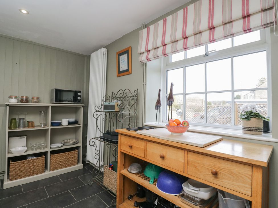 A kitchen with a microwave and shelves containing various dishes at Lavender Cottage in Bradford-on-Avon