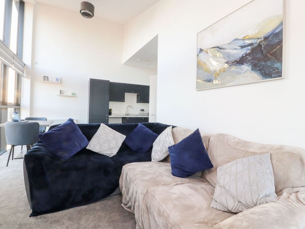 A living room with a sofa and kitchen area at Apartment 20, River View, Preston