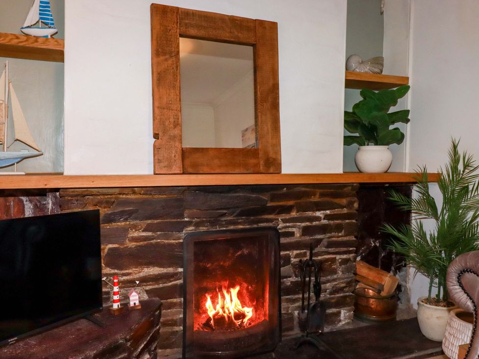 A living room with a fireplace and mirror at Chapel Cottage in Mevagissey