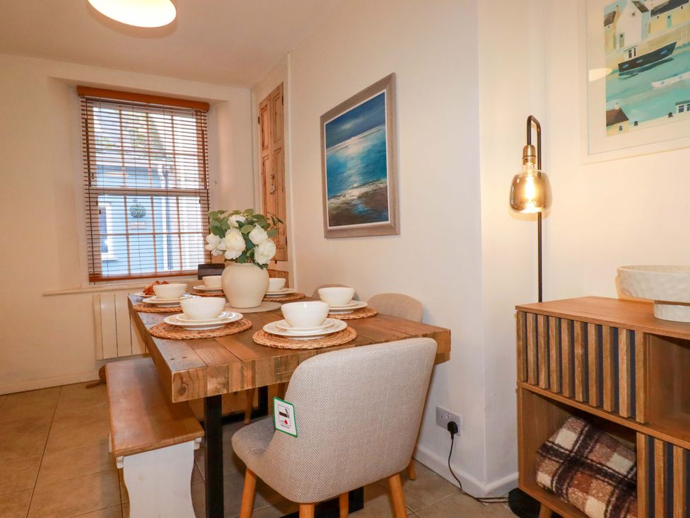 A dining room with a table set for meals at Chapel Cottage in Mevagissey