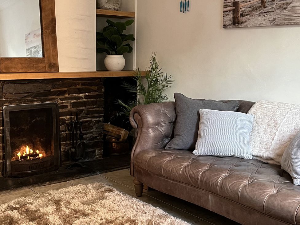 A living room with a sofa and a fireplace at Chapel Cottage in Mevagissey