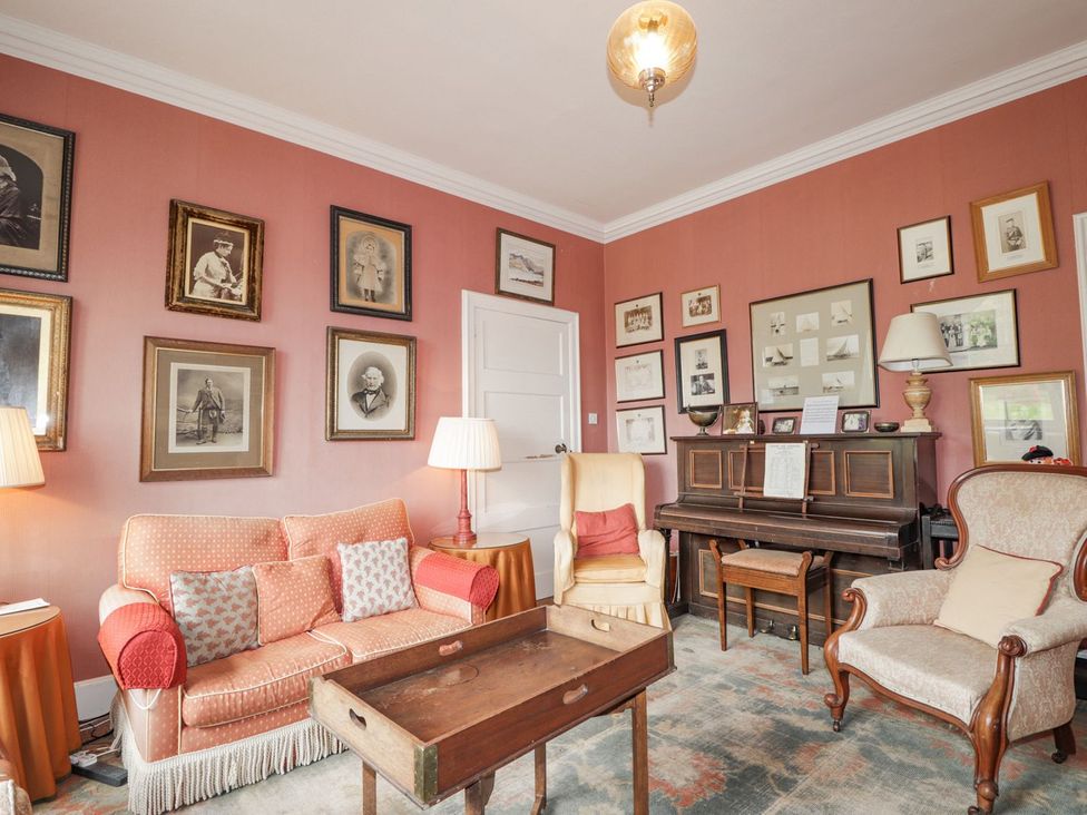 A living room with a sofa, armchair, table, and piano at Druidaig Lodge in Kyle