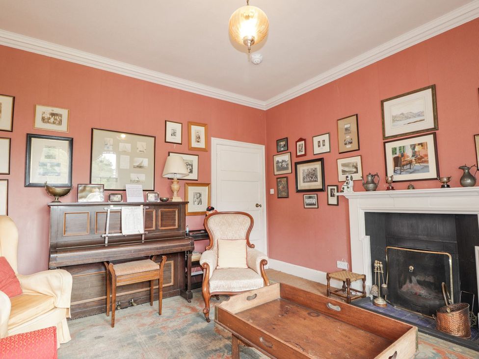 A living room with a piano and a fireplace at Druidaig Lodge in Kyle