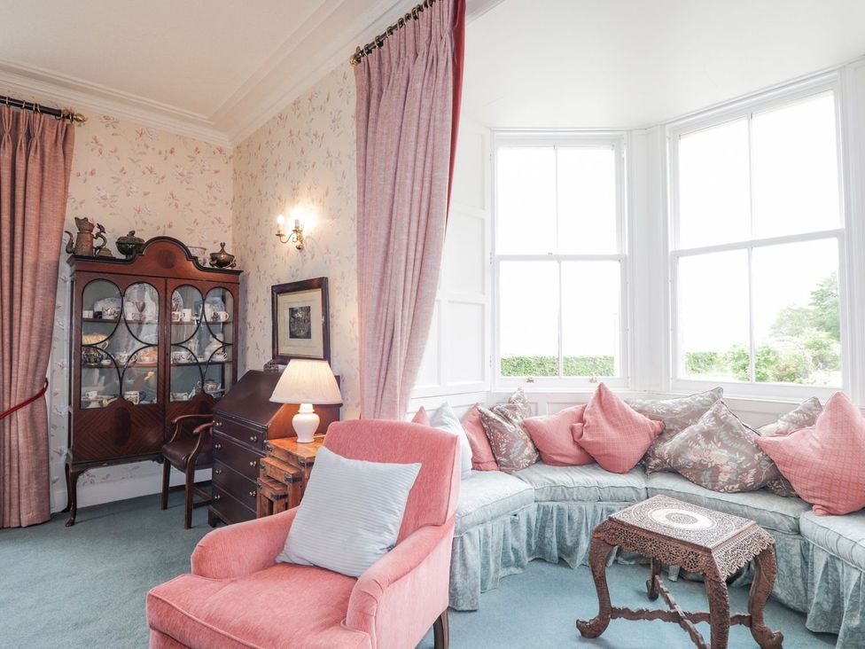 A living room with an armchair and display cabinet at Druidaig Lodge in Kyle