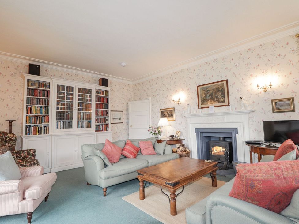 A living room with a fireplace and bookshelves at Druidaig Lodge in Kyle