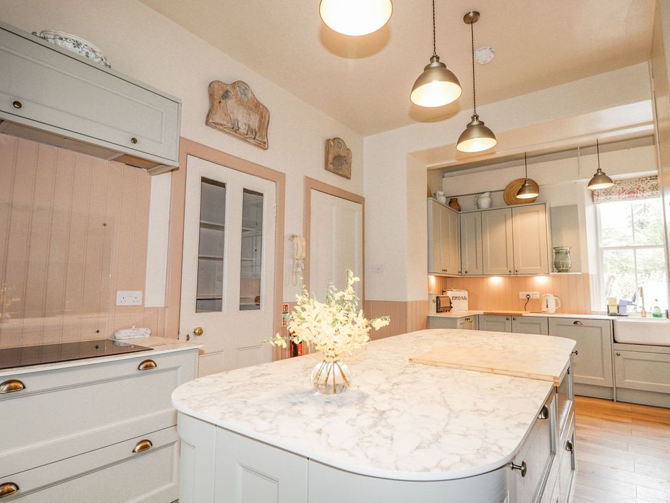 A kitchen with cabinets and a stone island at Druidaig Lodge in Kyle