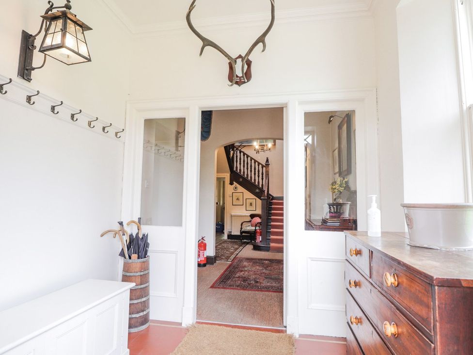 A hallway with a staircase and coat hooks at Druidaig Lodge in Kyle