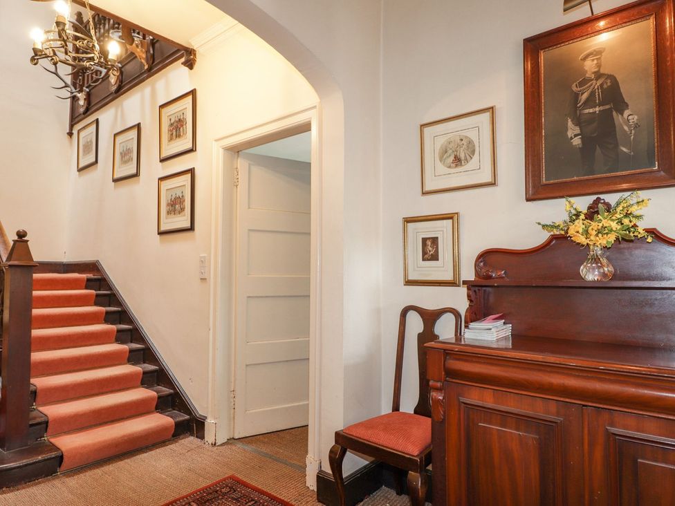 A hallway with a staircase and framed pictures at Druidaig Lodge in Kyle