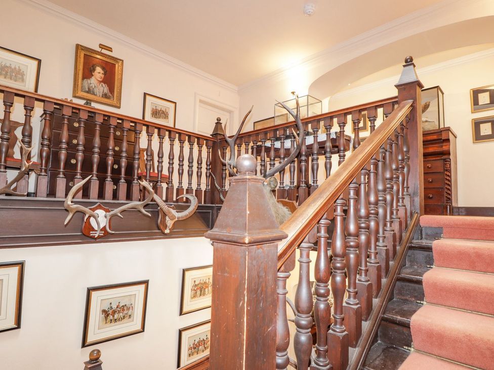 A staircase with antlers and framed pictures at Druidaig Lodge in Kyle